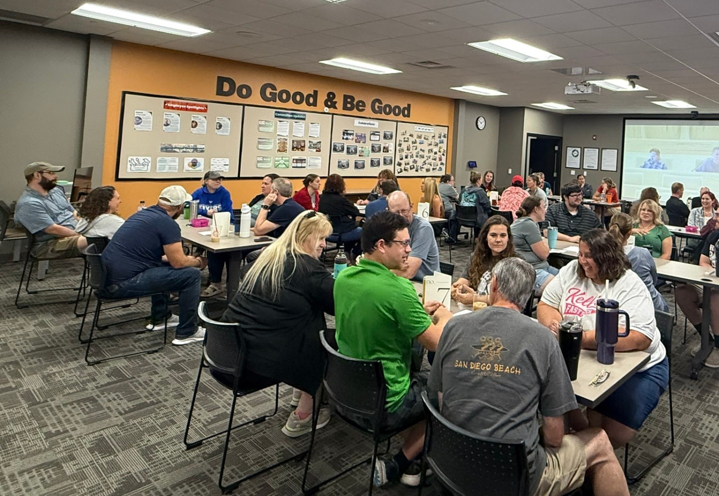 Daycos team gathered for a community event under the Do Good & Be Good wall